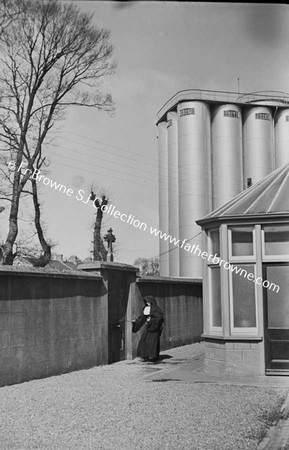 NUN ENTERING CONVENT  SILO IN THE BACKGROUND